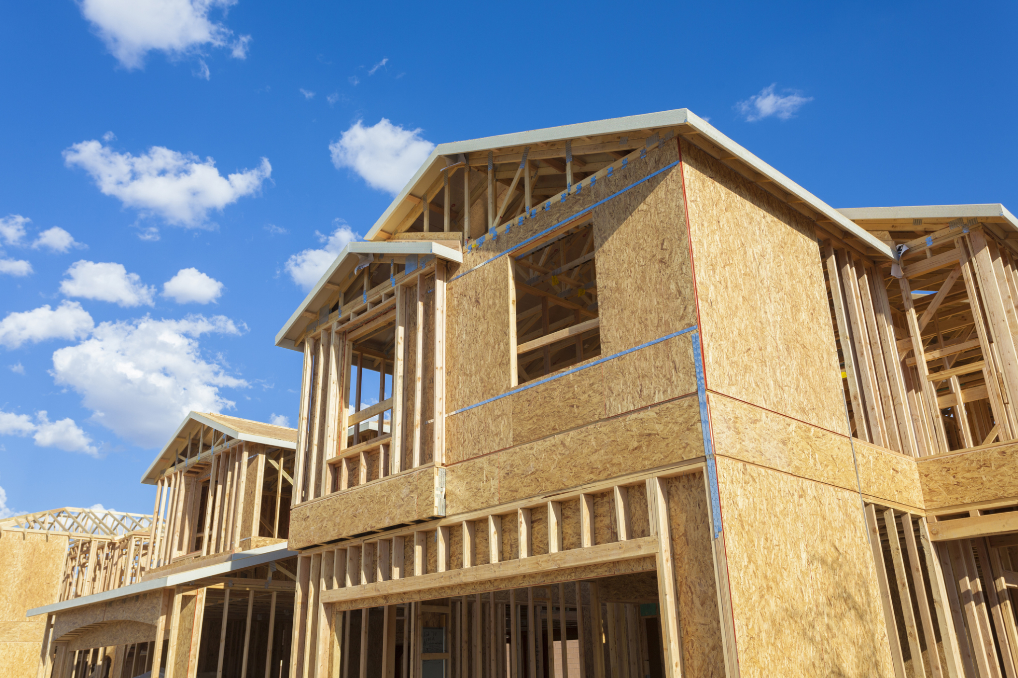 New home under construction with wood framing against blue sky